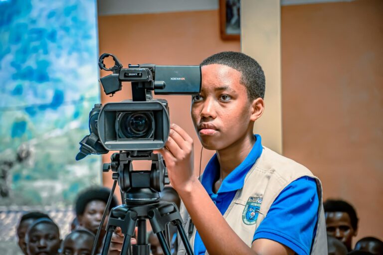 A dedicated young adult operates a video camera during an indoor event in Kigali, Rwanda.