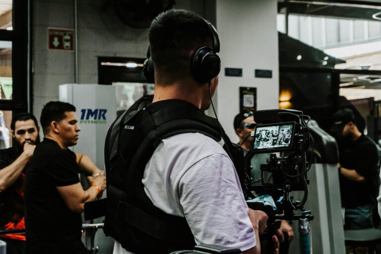 Back view of a filmmaker using a camera rig indoors with a focus on capturing event activities.